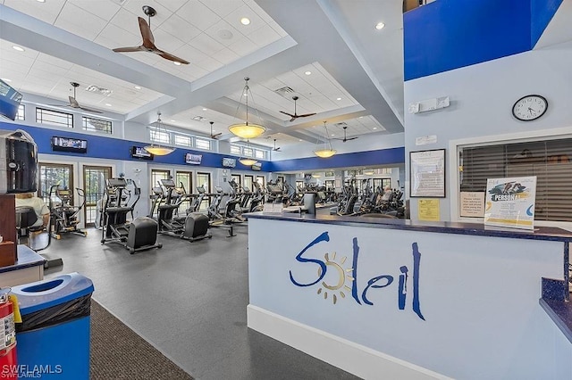 workout area with a tray ceiling, ceiling fan, and a high ceiling