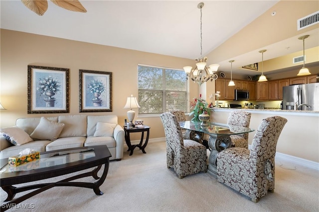 dining area with ceiling fan with notable chandelier, light colored carpet, and vaulted ceiling