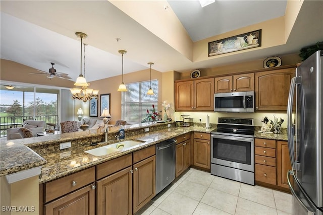 kitchen with sink, dark stone countertops, pendant lighting, ceiling fan with notable chandelier, and appliances with stainless steel finishes