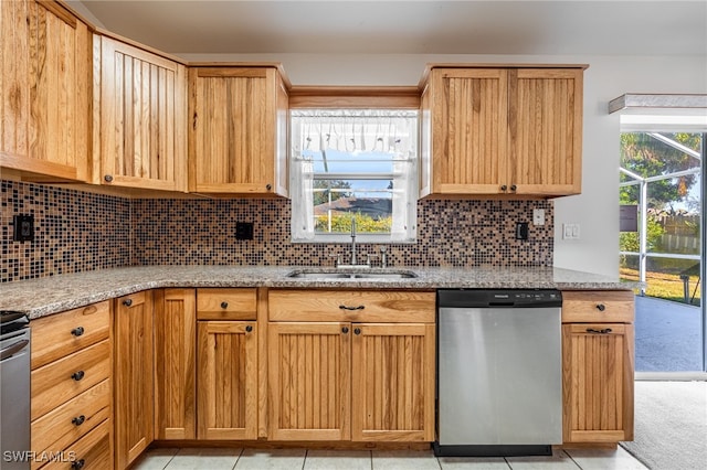 kitchen with dishwasher, a healthy amount of sunlight, light stone countertops, and sink