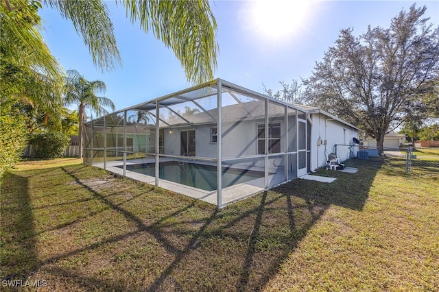 back of property featuring a yard, a fenced in pool, and glass enclosure