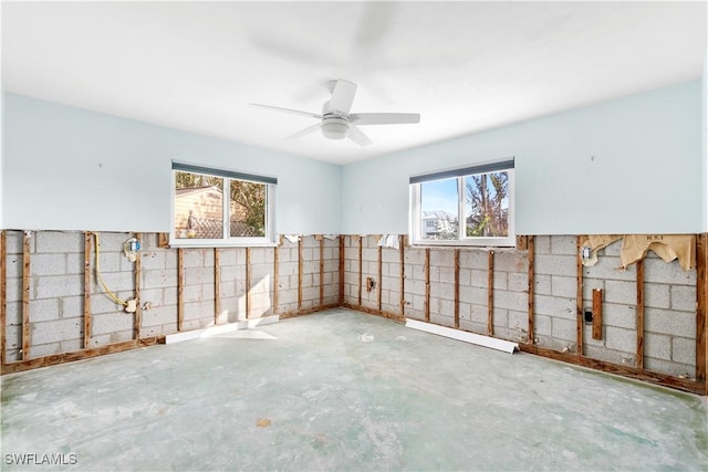 empty room with ceiling fan, concrete floors, and a healthy amount of sunlight