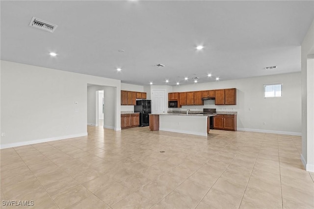 kitchen featuring a center island with sink, light tile patterned floors, black appliances, and sink