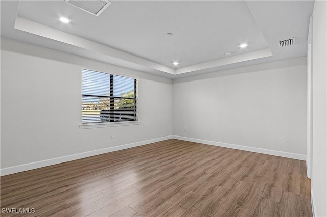 empty room with hardwood / wood-style floors and a raised ceiling