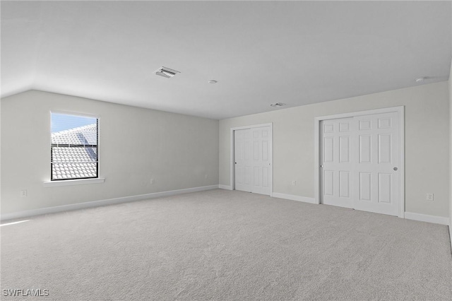 spare room with light carpet and vaulted ceiling