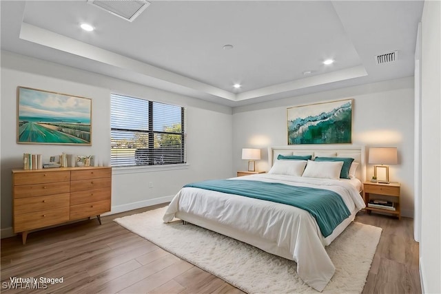 bedroom with a raised ceiling and hardwood / wood-style floors