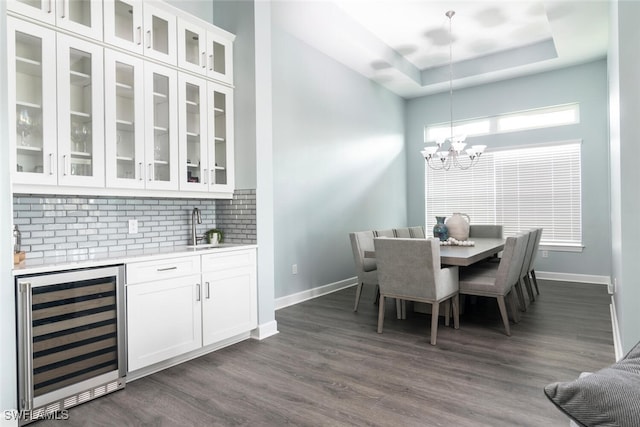 dining area with a raised ceiling, wine cooler, dark hardwood / wood-style flooring, a notable chandelier, and indoor wet bar