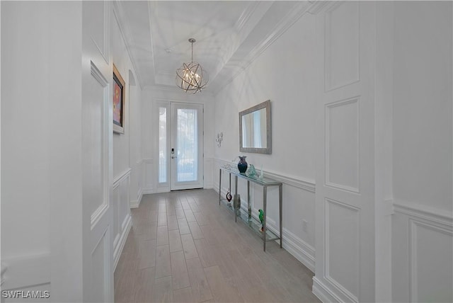 entrance foyer featuring crown molding, french doors, light hardwood / wood-style flooring, and a notable chandelier