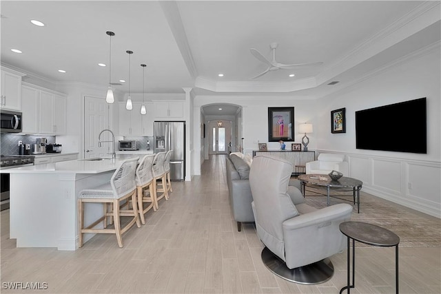 living room with ceiling fan, crown molding, and sink