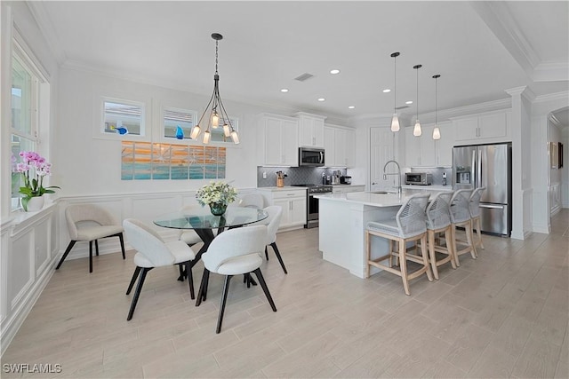 kitchen with white cabinets, hanging light fixtures, and appliances with stainless steel finishes