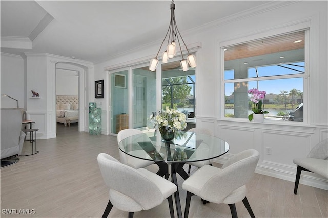 dining area featuring light hardwood / wood-style floors, ornamental molding, and a water view