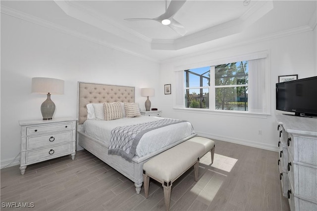 bedroom with a tray ceiling, crown molding, ceiling fan, and light hardwood / wood-style floors