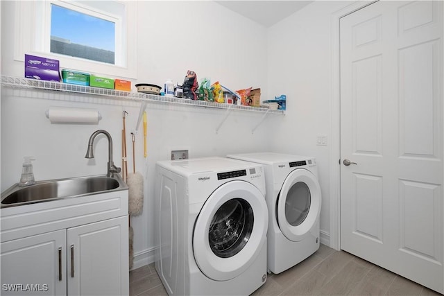 laundry area featuring washer and dryer, light hardwood / wood-style floors, cabinets, and sink