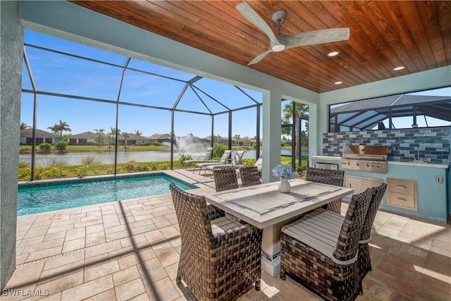 exterior space with glass enclosure, an outdoor kitchen, a water view, ceiling fan, and area for grilling