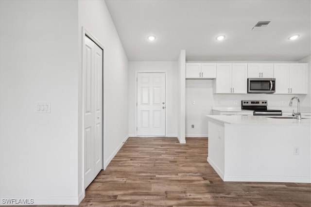 kitchen with appliances with stainless steel finishes, sink, white cabinetry, and hardwood / wood-style floors