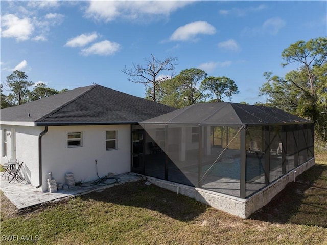 rear view of house featuring a lawn, glass enclosure, a patio area, and a swimming pool