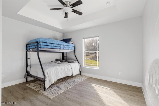 bedroom featuring wood-type flooring, a raised ceiling, and ceiling fan