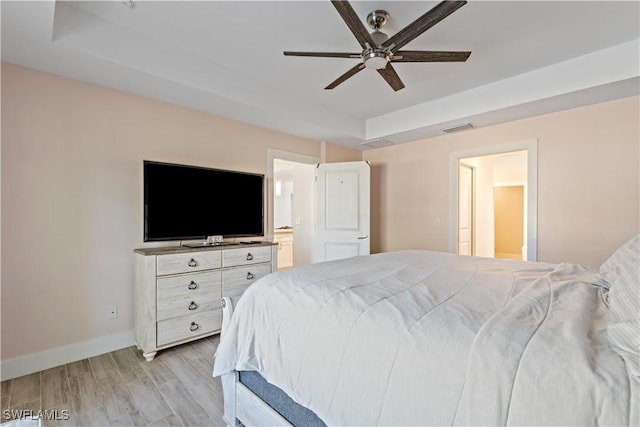 bedroom featuring connected bathroom, light hardwood / wood-style flooring, and ceiling fan