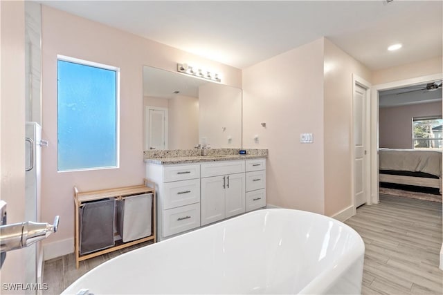 bathroom with hardwood / wood-style floors, a bathtub, ceiling fan, and vanity