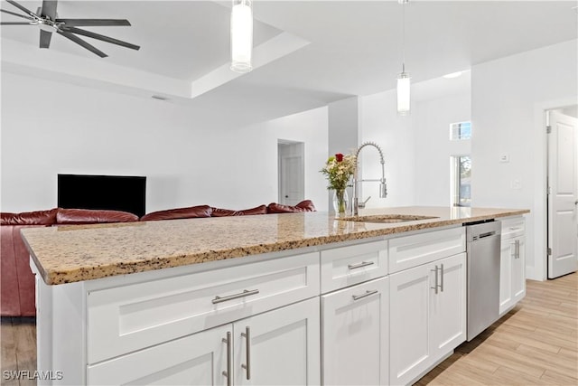 kitchen featuring dishwasher, a kitchen island with sink, white cabinets, hanging light fixtures, and light hardwood / wood-style flooring