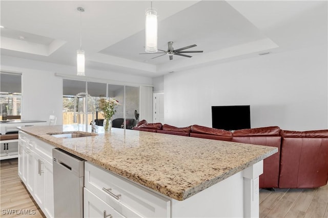 kitchen featuring dishwasher, pendant lighting, a raised ceiling, and an island with sink