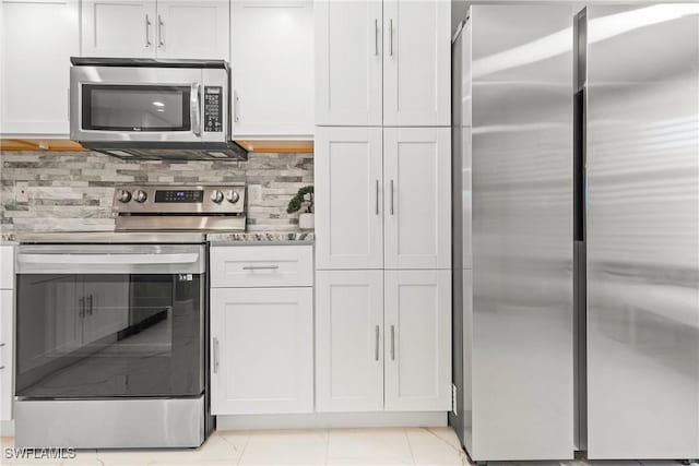 kitchen featuring backsplash, white cabinetry, stainless steel appliances, and light tile patterned floors