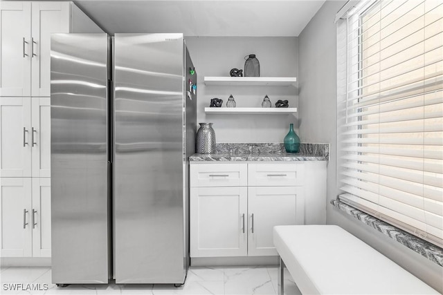 kitchen with white cabinets, stainless steel fridge, and light stone countertops