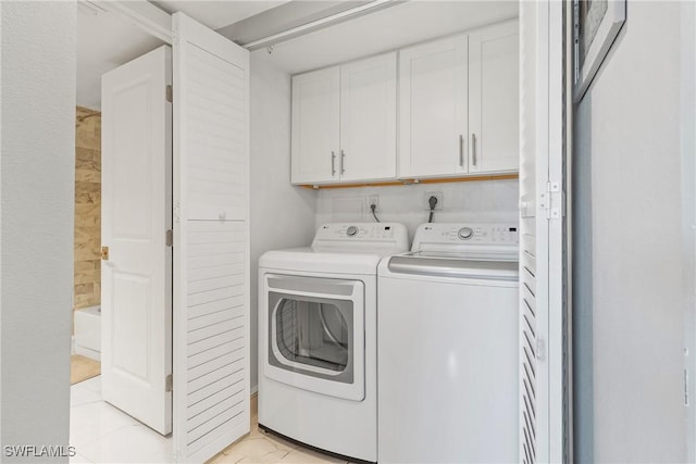 laundry room featuring cabinets, light tile patterned floors, and washing machine and clothes dryer