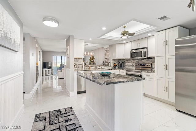 kitchen with ceiling fan, dark stone countertops, appliances with stainless steel finishes, tasteful backsplash, and white cabinetry