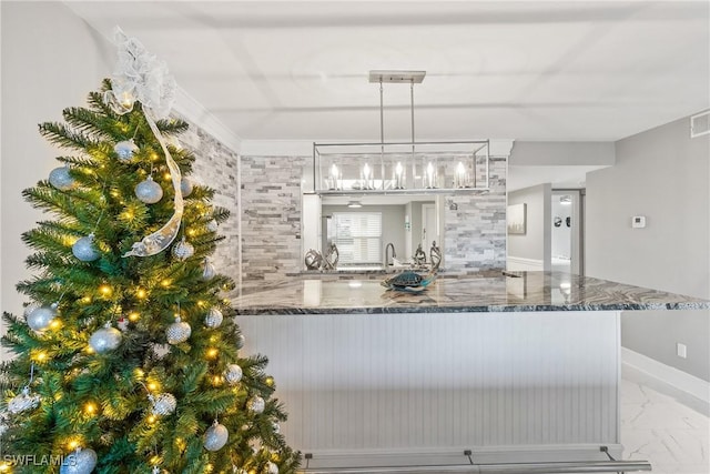 kitchen with kitchen peninsula, stone counters, sink, and decorative light fixtures