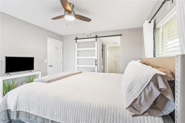 bedroom with a barn door and ceiling fan