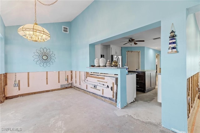 interior space featuring stainless steel refrigerator, a towering ceiling, ceiling fan with notable chandelier, and decorative light fixtures