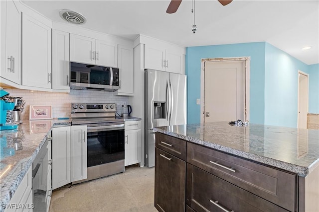 kitchen featuring white cabinets, ceiling fan, decorative backsplash, light stone countertops, and stainless steel appliances