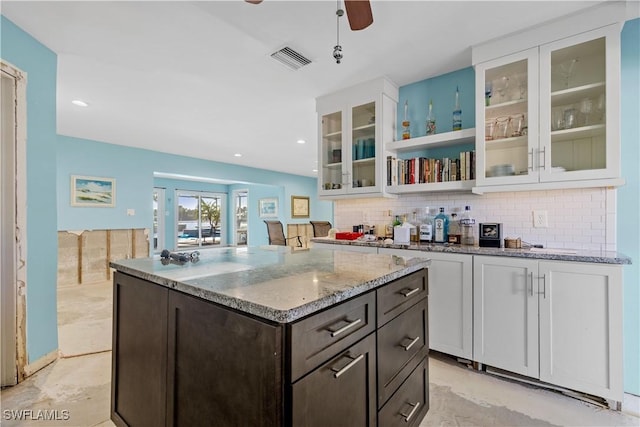 kitchen with white cabinets, dark brown cabinets, tasteful backsplash, and light stone countertops