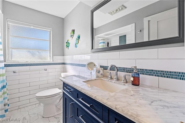 bathroom featuring tile patterned floors, vanity, toilet, and tile walls