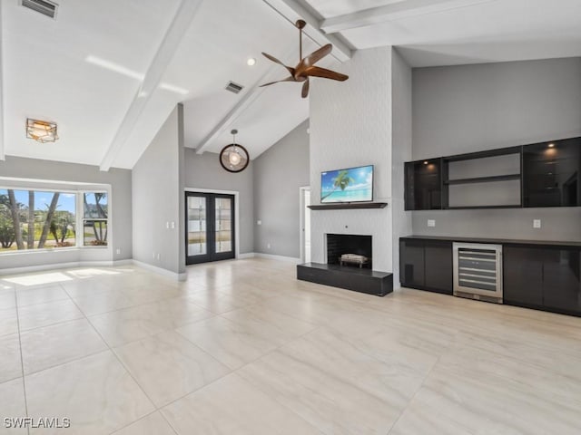 unfurnished living room featuring french doors, a fireplace, beverage cooler, high vaulted ceiling, and beamed ceiling