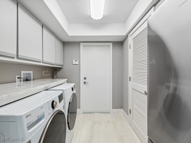 clothes washing area featuring washer and dryer and cabinets