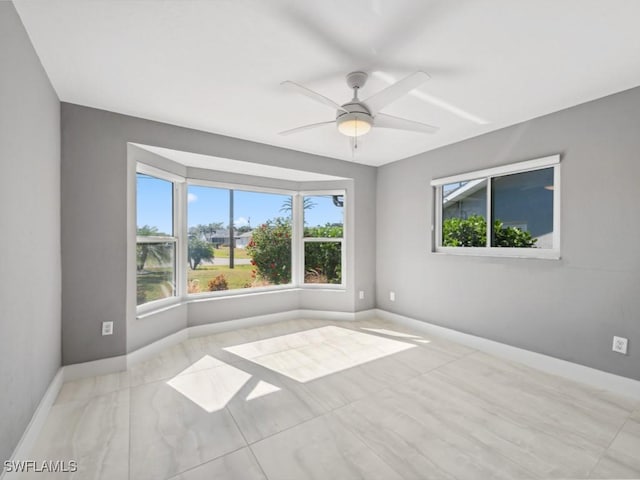 empty room with ceiling fan and plenty of natural light