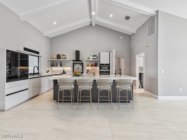 kitchen with beamed ceiling, a spacious island, a kitchen bar, and sink