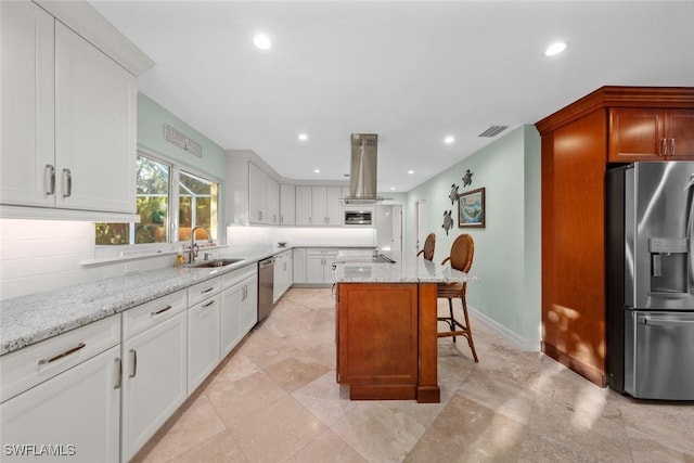 kitchen featuring sink, appliances with stainless steel finishes, white cabinetry, light stone counters, and a kitchen island