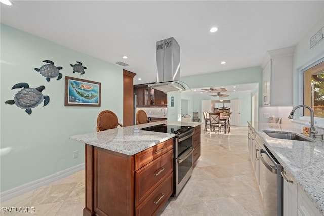 kitchen featuring light stone counters, stainless steel appliances, tasteful backsplash, a sink, and island range hood