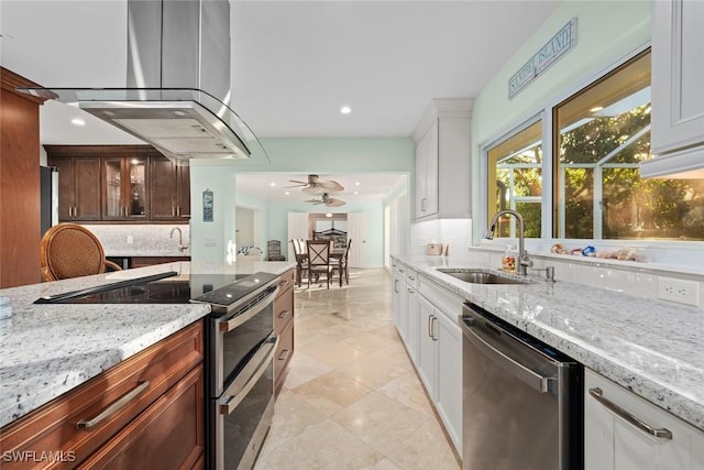 kitchen with appliances with stainless steel finishes, a sink, light stone counters, and tasteful backsplash