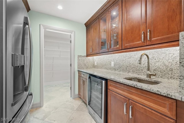 kitchen featuring beverage cooler, light stone counters, a sink, and stainless steel fridge with ice dispenser