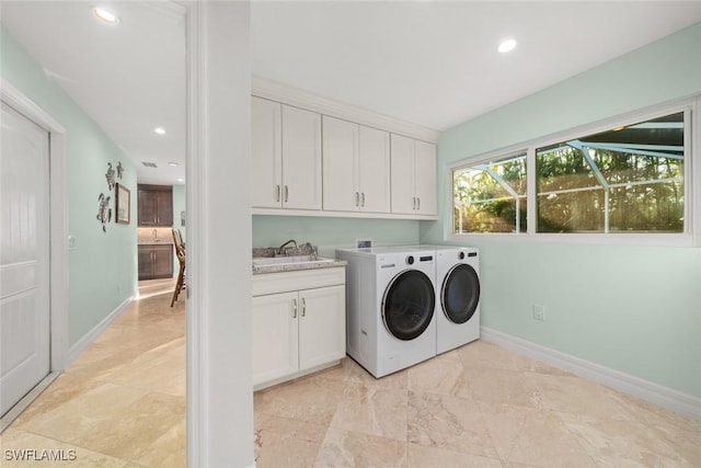 laundry room with cabinets, washing machine and dryer, and sink