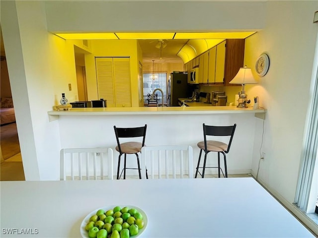 kitchen with a kitchen bar, kitchen peninsula, and appliances with stainless steel finishes