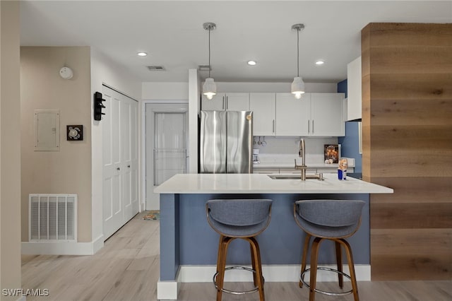 kitchen featuring white cabinetry, stainless steel fridge, decorative light fixtures, electric panel, and sink