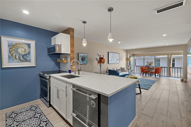 kitchen with white cabinetry, kitchen peninsula, range with two ovens, hanging light fixtures, and sink