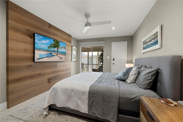 bedroom with ceiling fan, access to exterior, and wooden walls