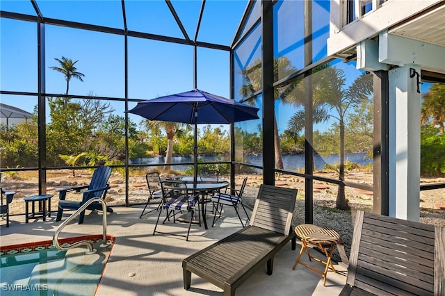 view of patio / terrace featuring a water view and glass enclosure