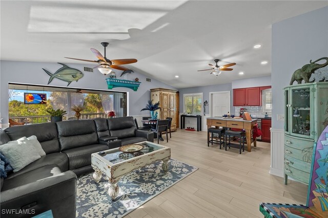 living room with ceiling fan, lofted ceiling, and light wood-type flooring